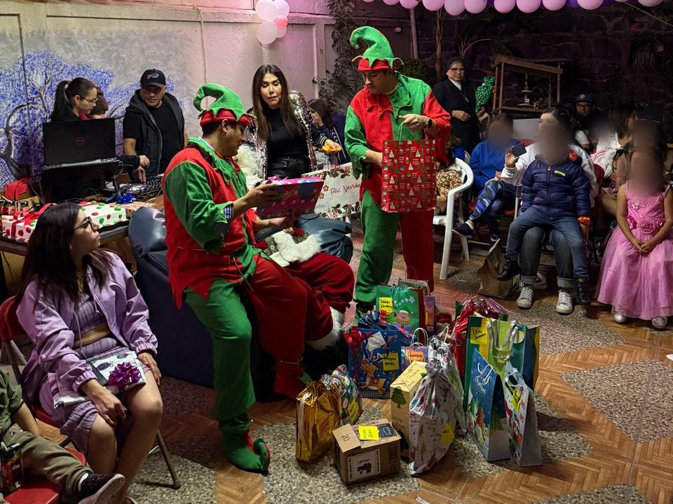 Duendes reparten regalos a niñas y niños en una casa hogar