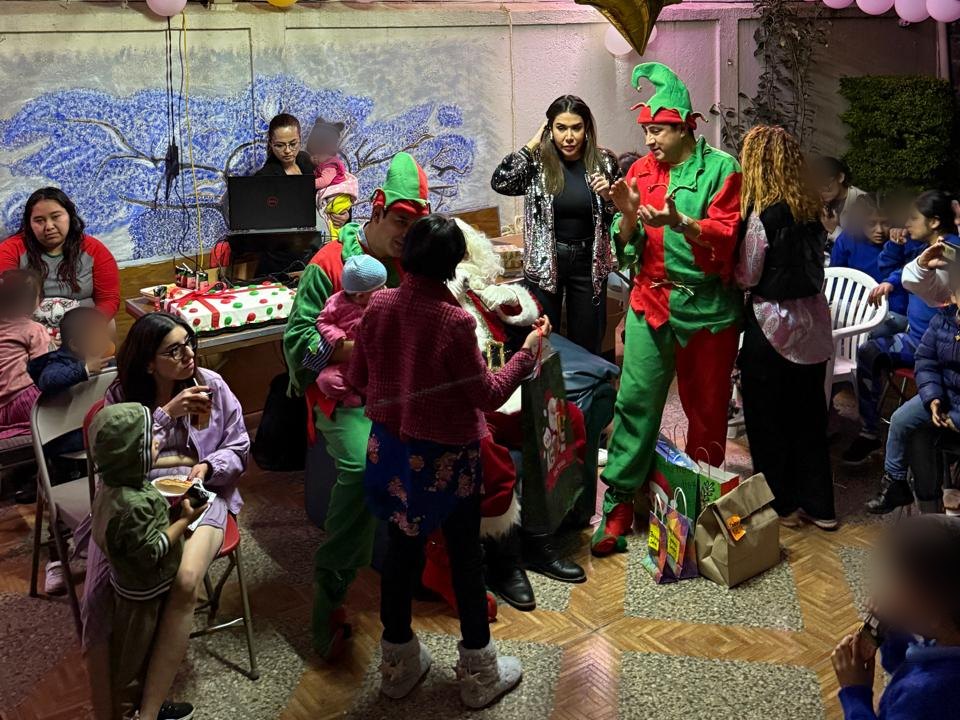 Santa Claus y dos duendes entregan regalos durante la posada navideña de Las Cenas de Isabella en una casa hogar